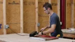 Man using the black IR Paint Stripper on a window sash in a workshop